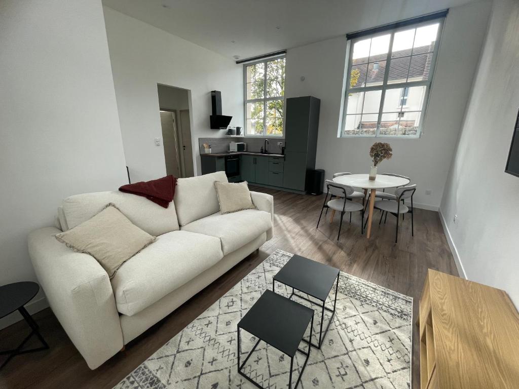 sala de estar con sofá blanco y mesa en Appartement avec terrasse, en Dole
