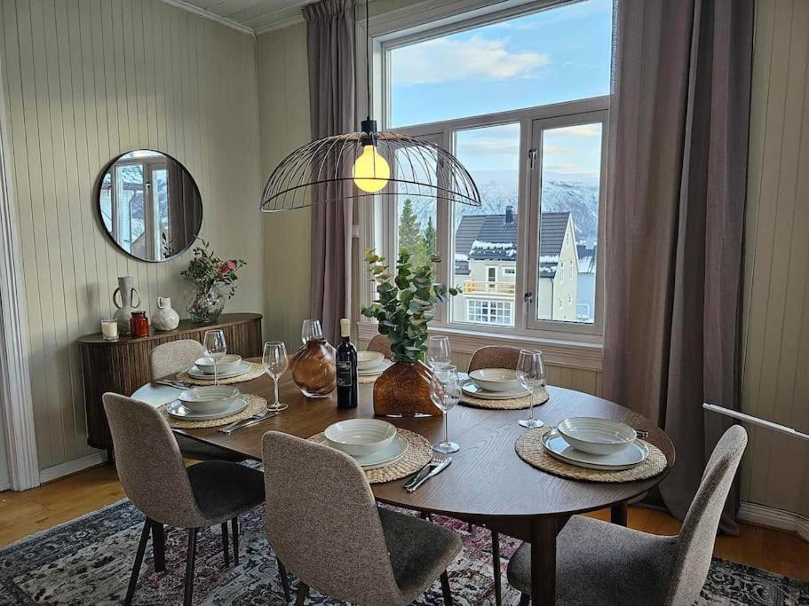 een eettafel met stoelen en een groot raam bij Amazing Tromsø city apartment with free parking and lovely city views! in Tromsø