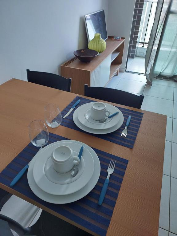 a wooden table with plates and silverware on it at APARTAMENTO PROXIMO À UFPE in Recife