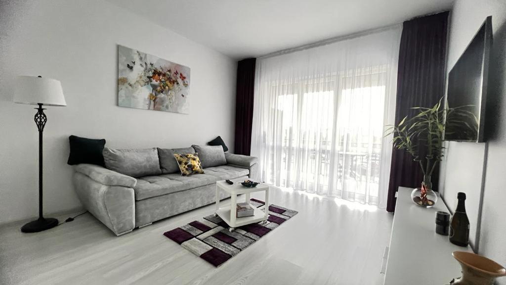 uma sala de estar com um sofá e uma janela em ONE Apartment Militari em Bucareste