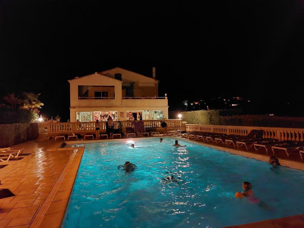 un grupo de personas en una piscina por la noche en Village de gîtes La Fontinelle en Bessas