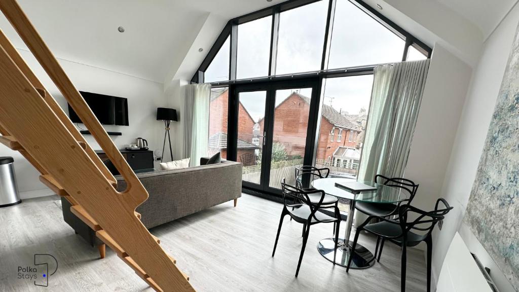 ein Wohnzimmer mit einem Tisch und Stühlen sowie einem großen Fenster in der Unterkunft The Stables, Chester - Luxury Apartments by PolkaStays in Chester