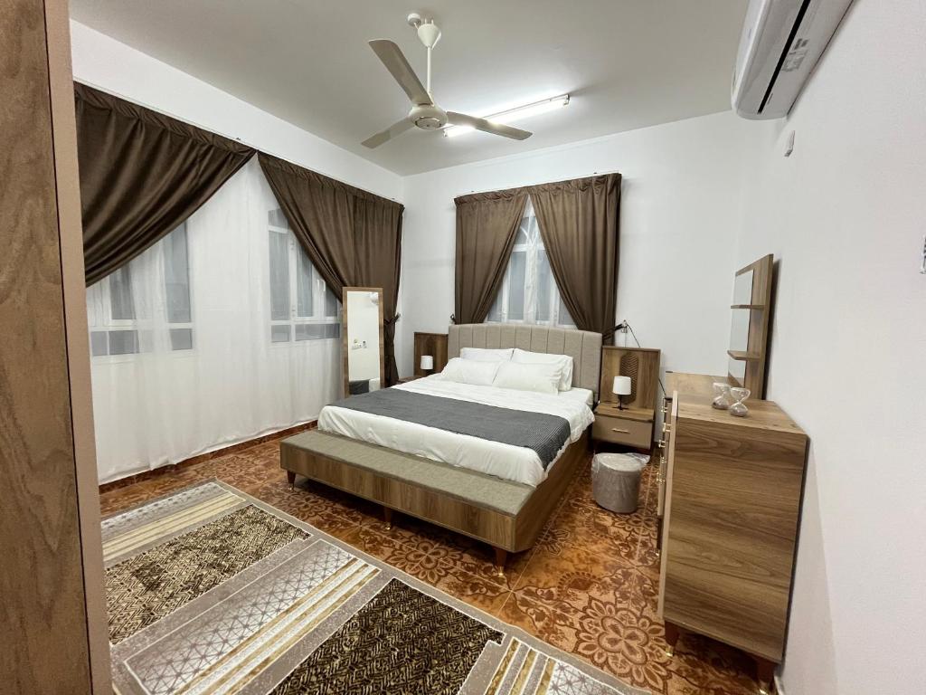 1 dormitorio con 1 cama y ventilador de techo en Relaxation Oasis, en Al Ḩamrāʼ