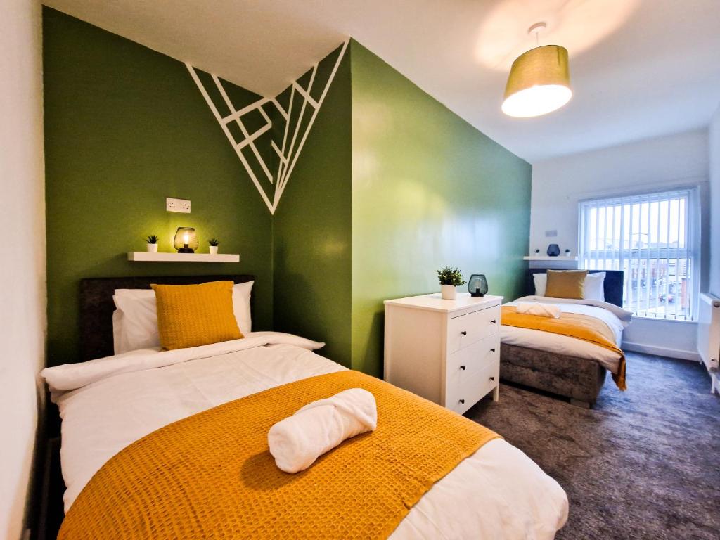 a bedroom with two beds and a green wall at Modern and spacious apartment! in Liverpool