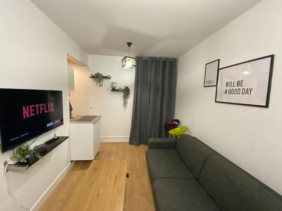 a living room with a couch and a flat screen tv at Appartement cosy 10 min stade de France in Saint-Denis