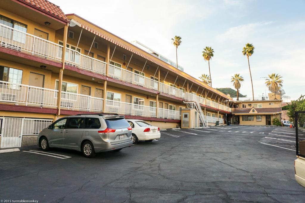 dois carros estacionados num parque de estacionamento em frente a um hotel em Hollywood La Brea Inn em Los Angeles