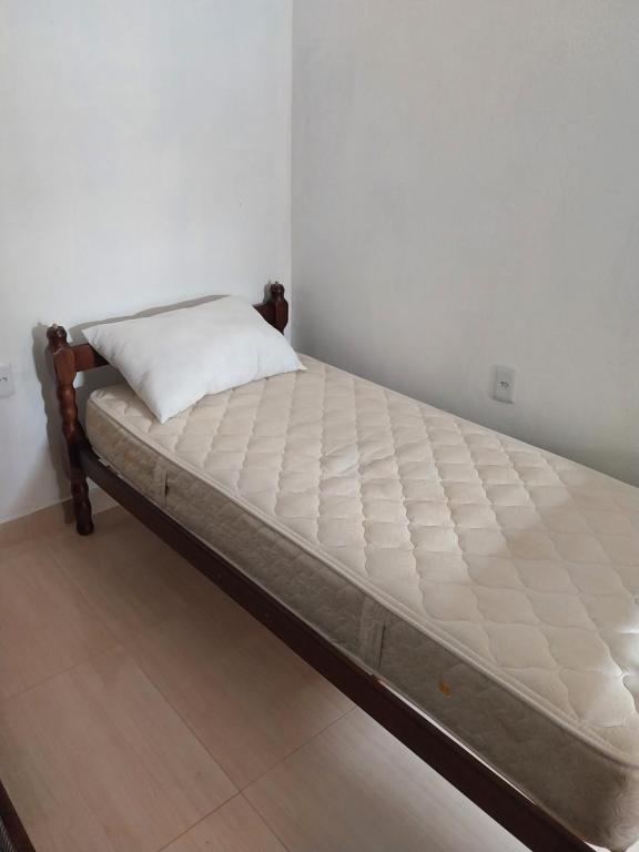 una cama en una esquina de una habitación en Kitnet Indaiá en Bertioga
