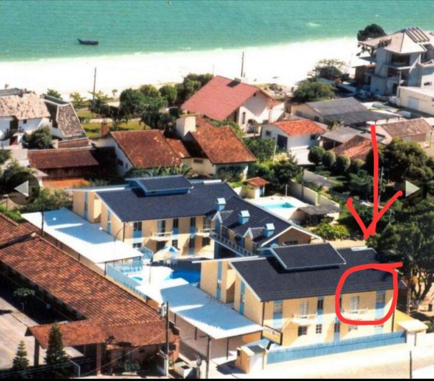 dom z czerwoną strzałą nad oceanem w obiekcie AP com Piscina em Porto Belo w mieście Porto Belo