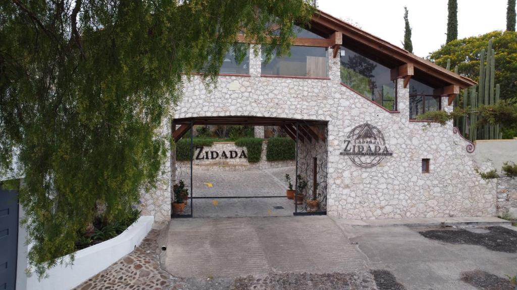 a stone building with a door and a tree at Zidada Hotel and Chalets in Bernal