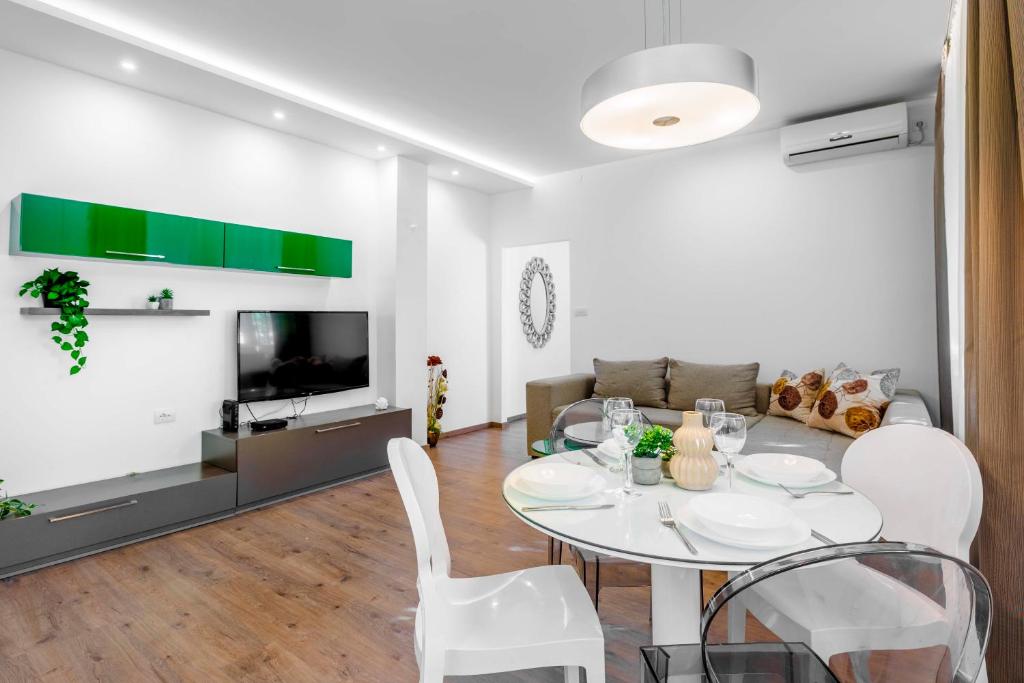 - un salon avec une table, des chaises et une télévision dans l'établissement Silver Apartment, à Novi Sad