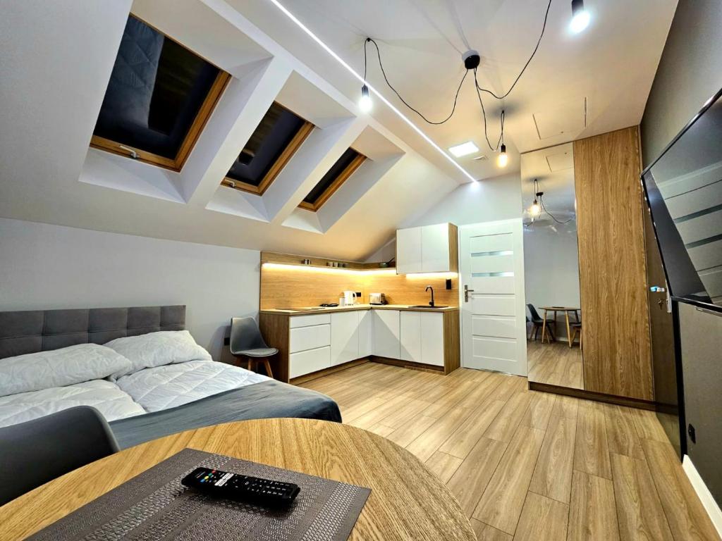 a bedroom with a bed and a table and a kitchen at Apartamenty na 102 in Iława