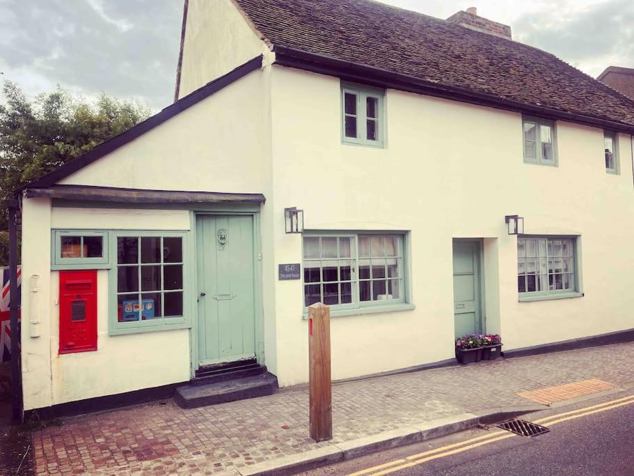 uma casa branca com portas vermelhas e azuis numa rua em Beautiful Countryside Cottage - Old Post Office em Cobham