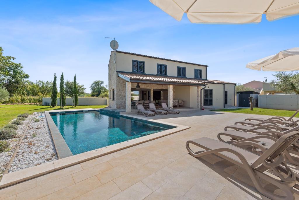a swimming pool in front of a house with chairs at Villa Stellar in Brtonigla
