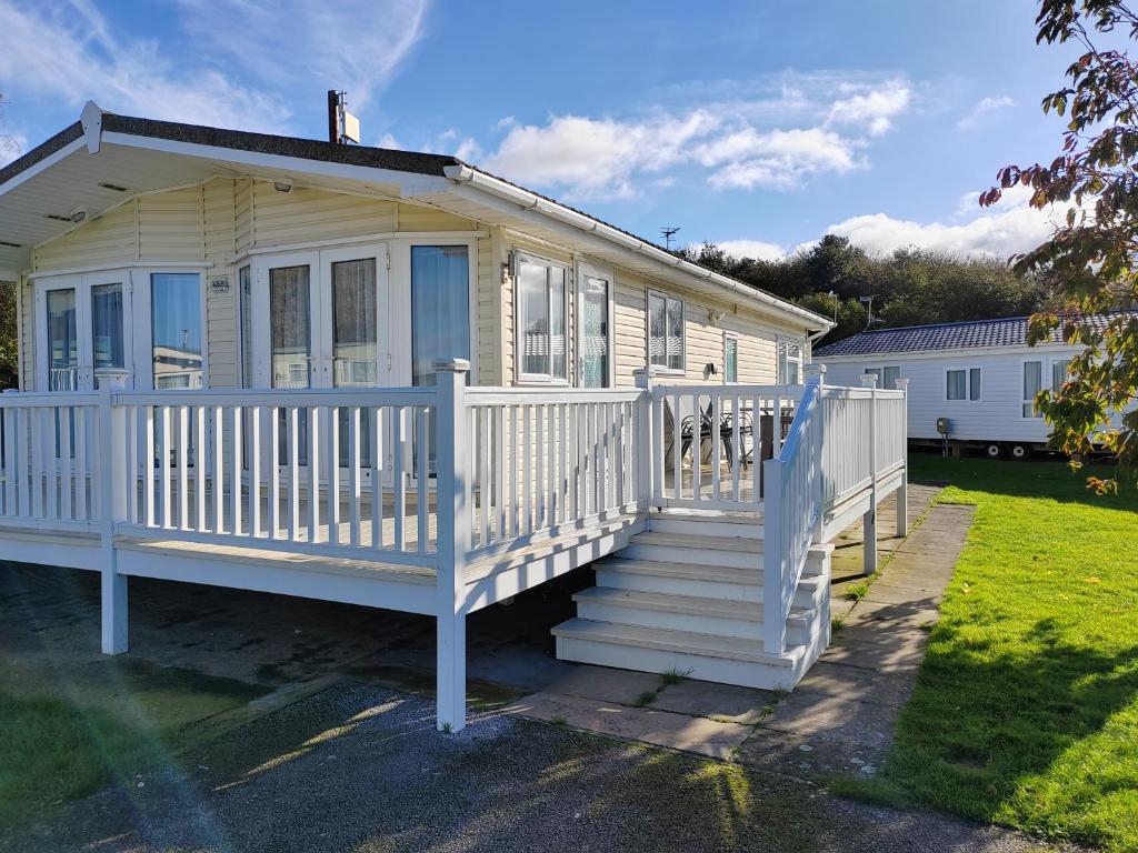 a white house with a white porch and stairs at Dog Friendly 8 Berth Lodge, 600 Yard's From The Beach In Hunstanton in Hunstanton