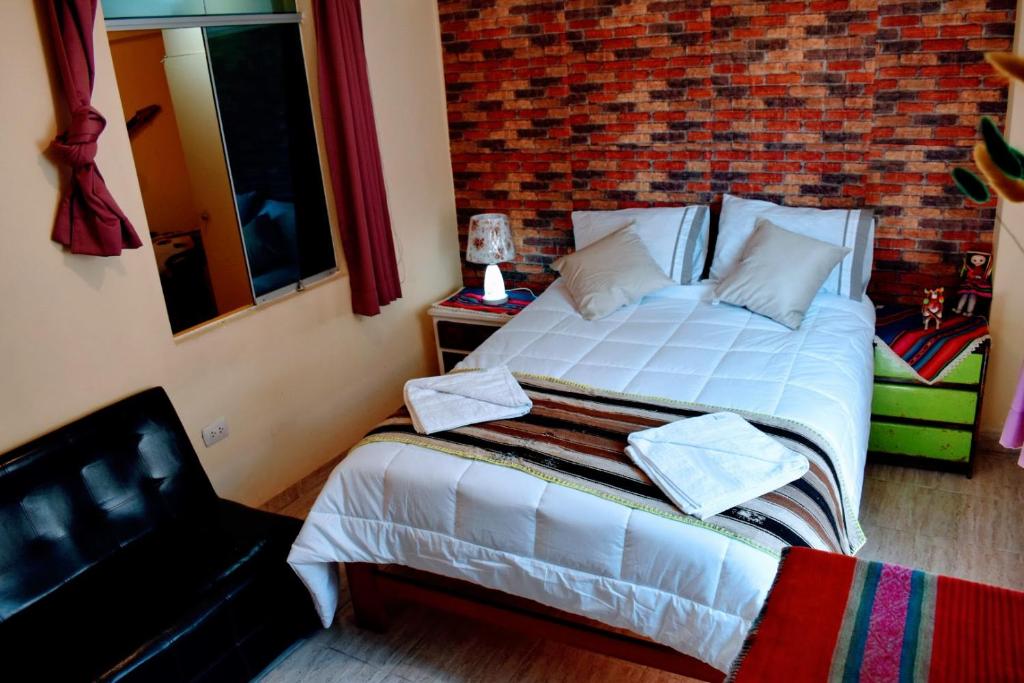 a bedroom with a bed and a brick wall at LA CUSQUEÑITA in Cusco
