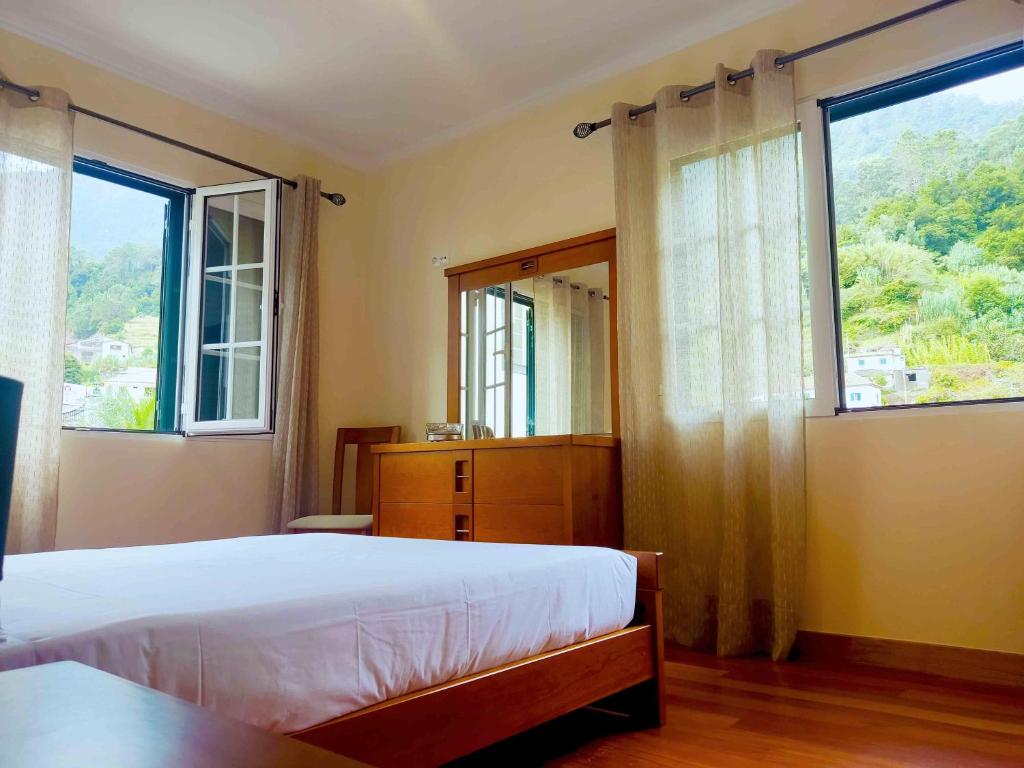 a bedroom with two beds and a large window at Casa da Ribeira in Senhora do Rosário