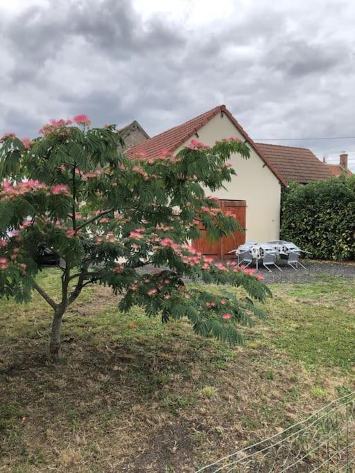 une maison avec un arbre et des fleurs roses devant elle dans l'établissement Maison accueillante avec cour et parking privé, à Châtillon-sur-Cher