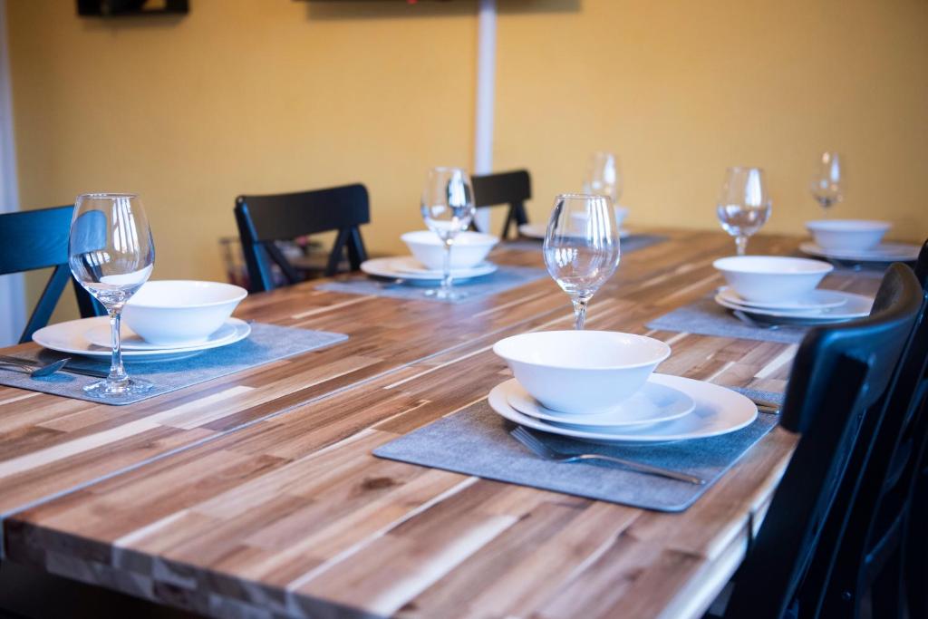 a wooden table with plates and wine glasses on it at Buttercup House in Saint Neots