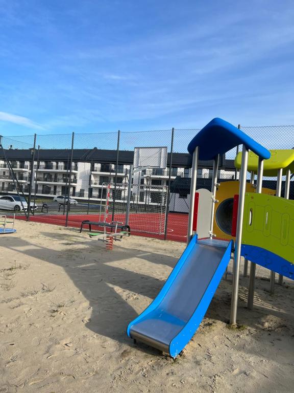 un parque infantil con un tobogán en la arena en LuxApart Apartamenty Jantar, en Jantar