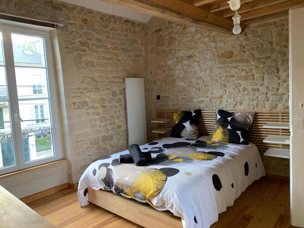 a bedroom with a large bed in a stone wall at Charmante petite maison in Saint-Vigor-le-Grand