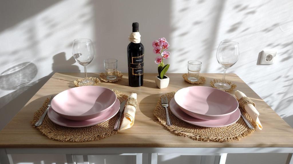 einen Tisch mit zwei rosa Platten und einer Flasche Wein in der Unterkunft Romantic Bijoux in Central Sofia in Sofia