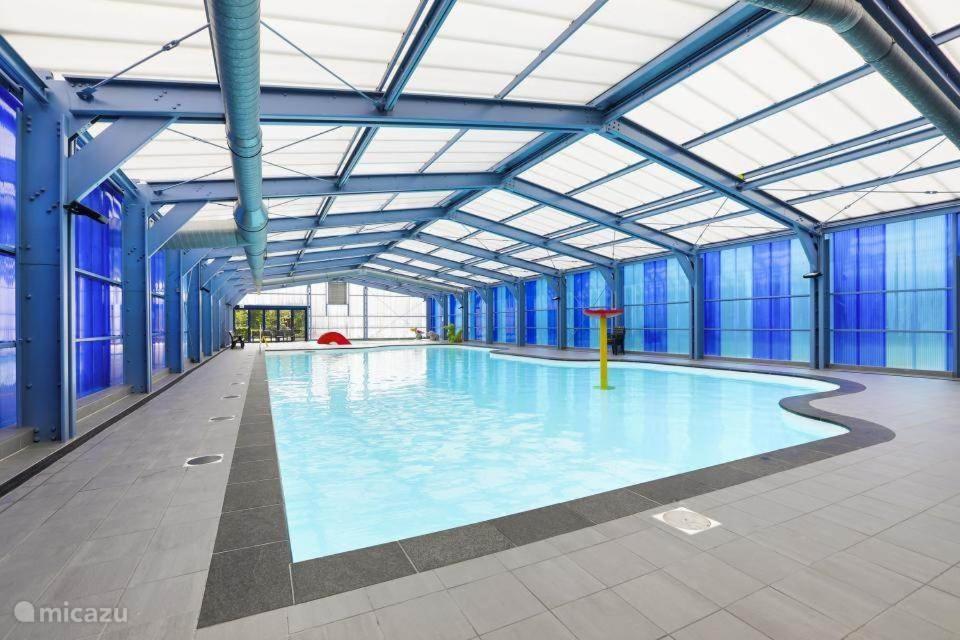 a large indoor swimming pool with blue walls and windows at Juromi 42 in Gramsbergen