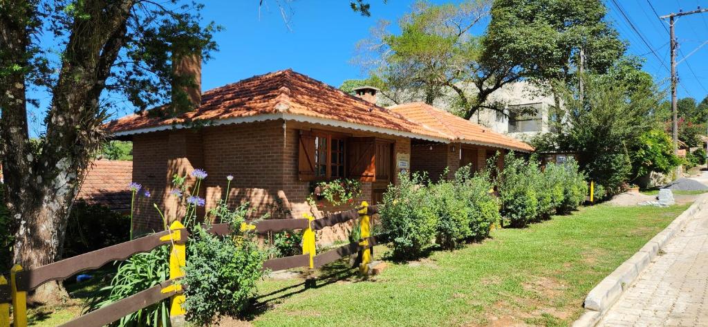 une maison avec une clôture et une rangée de plantes dans l'établissement Chales Encanto Suíço, à Monte Verde