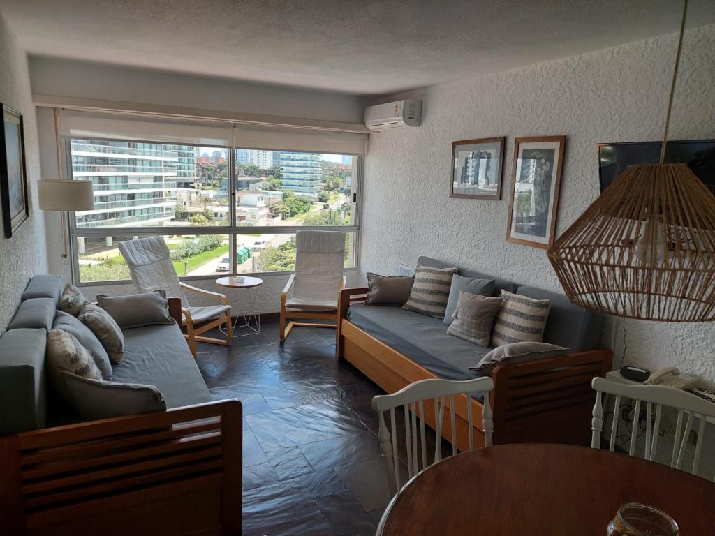 sala de estar con sofá, sillas y ventana en Apartamento en Torre Del Plata II, en Punta del Este