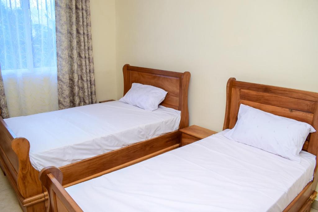 2 camas individuales en una habitación con ventana en Bahari Pride Apartment, en Mombasa