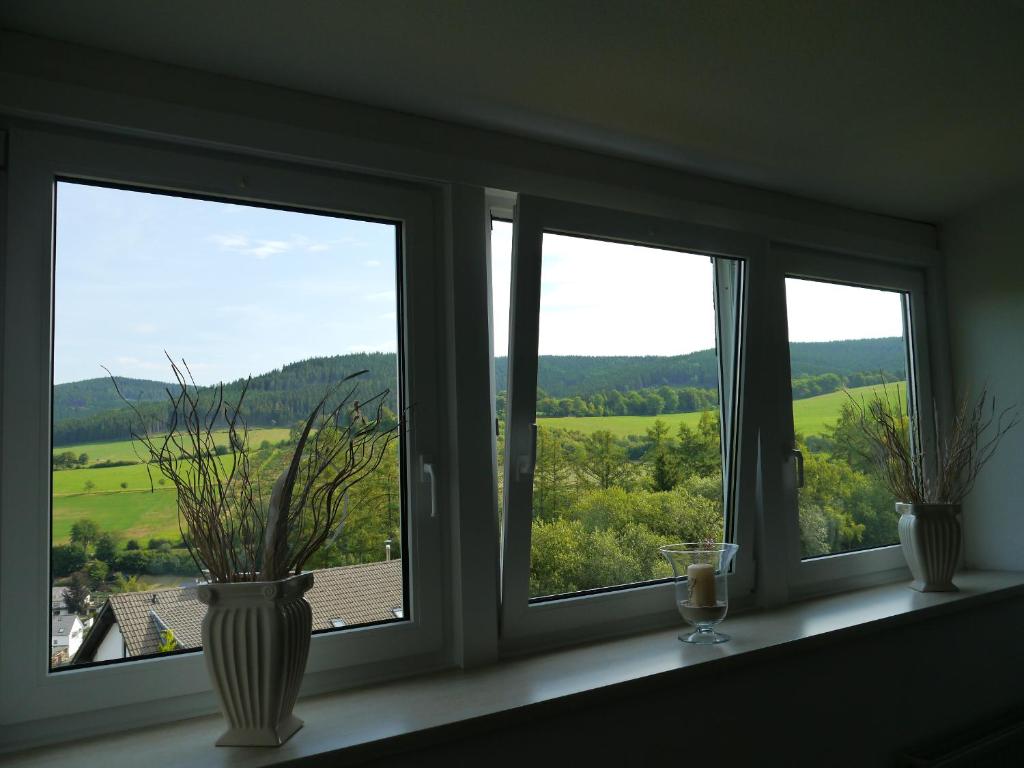 una ventana con tres jarrones sentados en un alféizar de la ventana en Unter den Wolken, en Winterberg