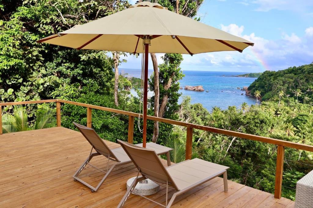 eine Terrasse mit 2 Stühlen und einem Sonnenschirm in der Unterkunft Blue Whale Villa - Deluxe Suite in Calibishie