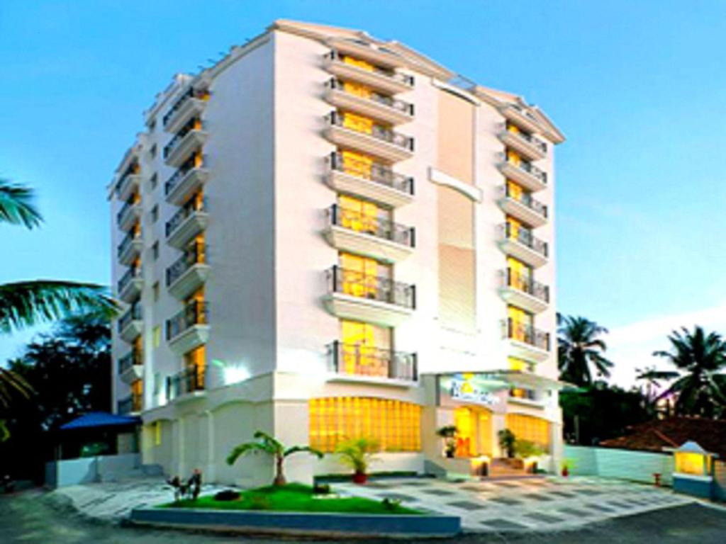 a tall building with palm trees in front of it at SFS Homebridge @ City in Trivandrum