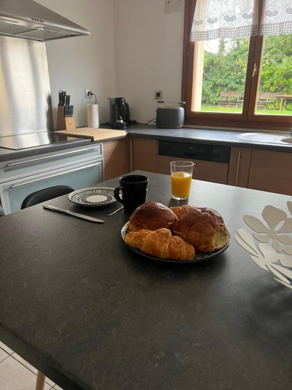 una mesa con un plato de pan y un vaso de zumo de naranja en Entre terre et mer, en Rinxent