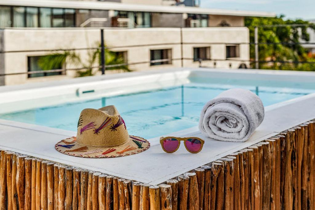 un par de sombreros y gafas de sol junto a una piscina en Hotel Banana Boutique & Spa by Paradise Hotels - 5th Av Playa del Carmen, en Playa del Carmen