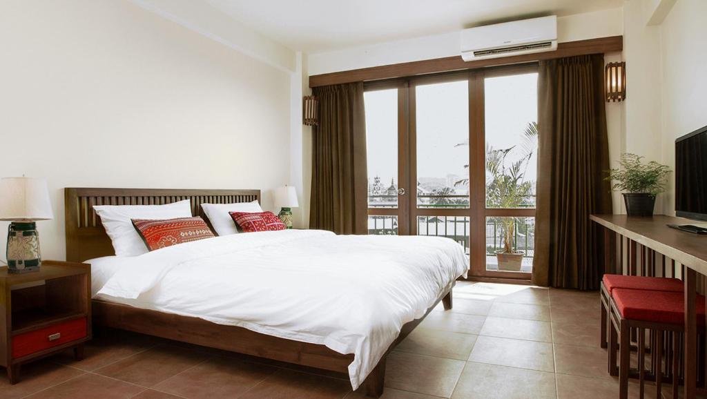 a bedroom with a large white bed and a balcony at Green Tiger House in Chiang Mai