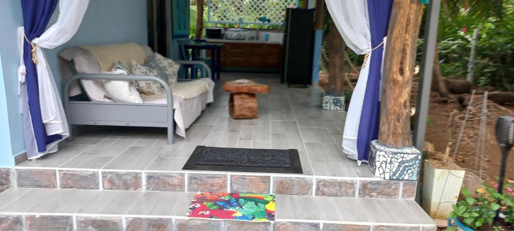 eine Veranda mit einem Sofa und einem Stuhl auf einem Fliesenboden in der Unterkunft Casa Katharina in Cahuita
