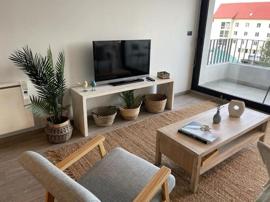 sala de estar con TV de pantalla plana y mesa en Acogedor departamento, en Puerto Varas