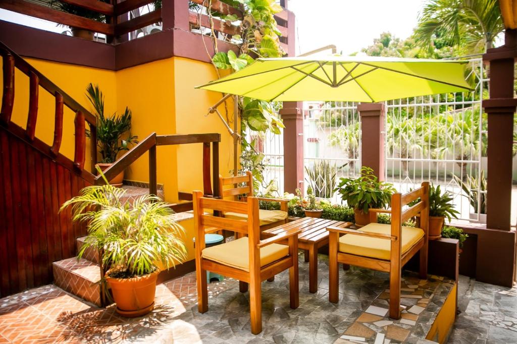 un patio con mesa, sillas y sombrilla en Hotel BAHÍA, en Tela