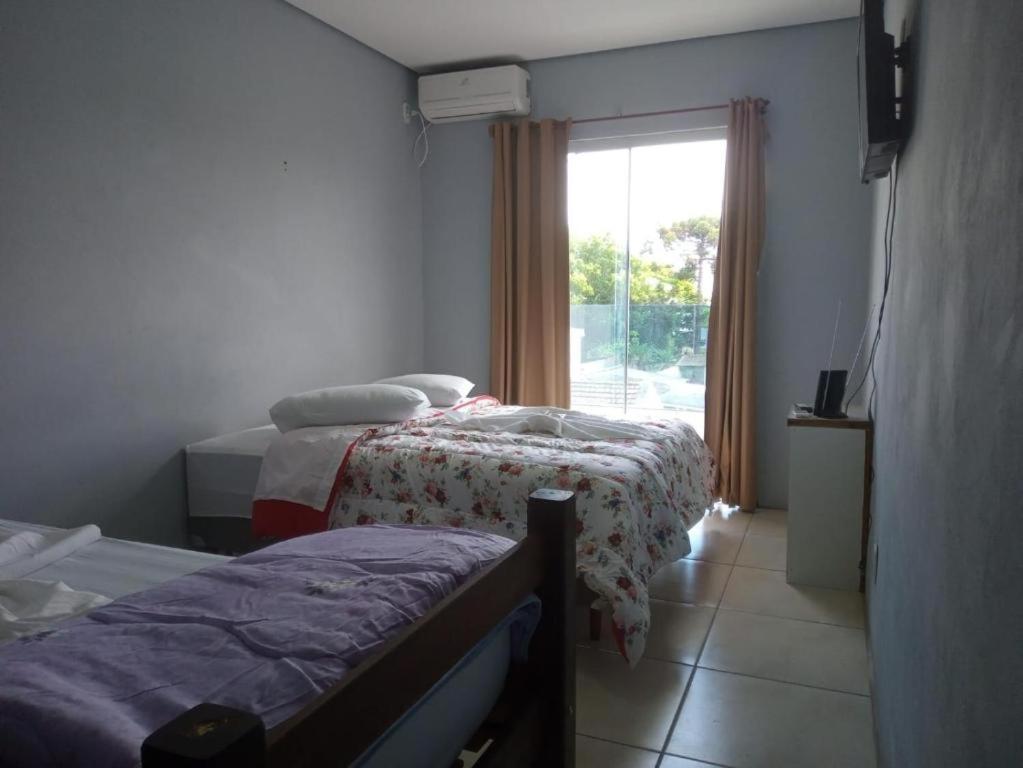 a hotel room with two beds and a window at Hotel Caçula São Gabriel in São Gabriel