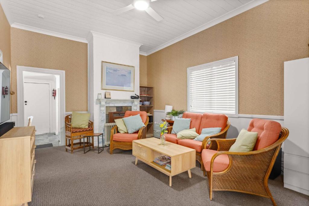 a living room with orange chairs and a fireplace at The Gunyah by Experience Jervis Bay in Huskisson