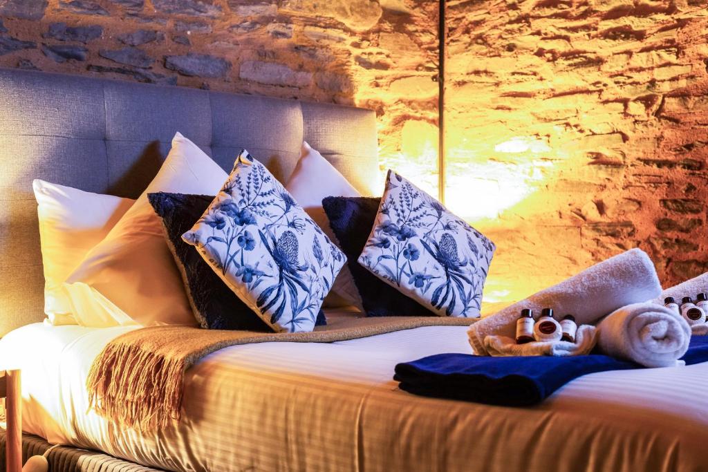 1 dormitorio con 1 cama con almohadas azules y blancas en Reillys Wines Heritage Cottages, en Mintaro