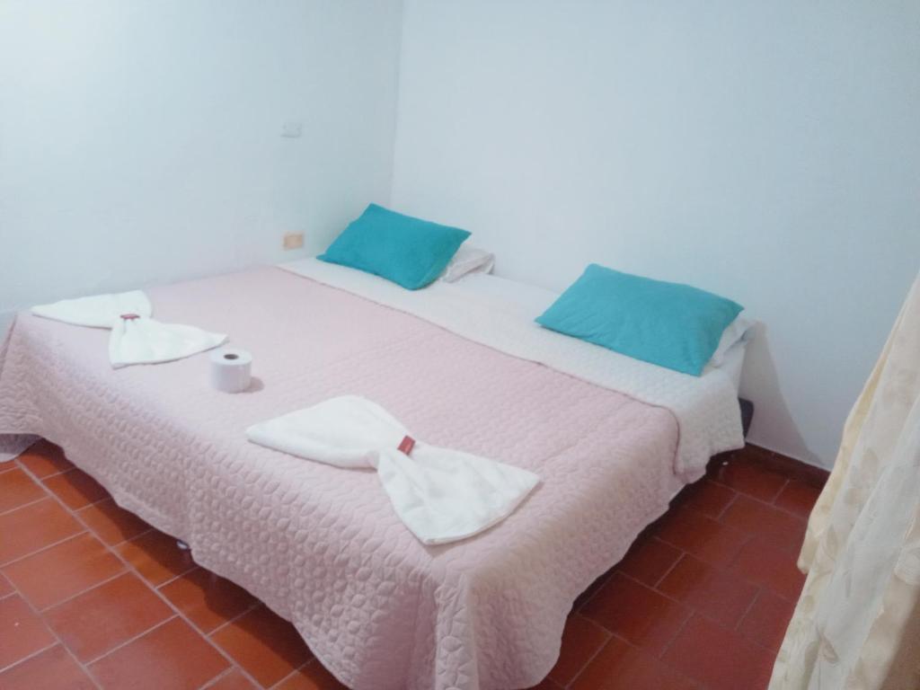 Una cama blanca con almohadas azules y toallas. en Hostal central en Villa de Leyva