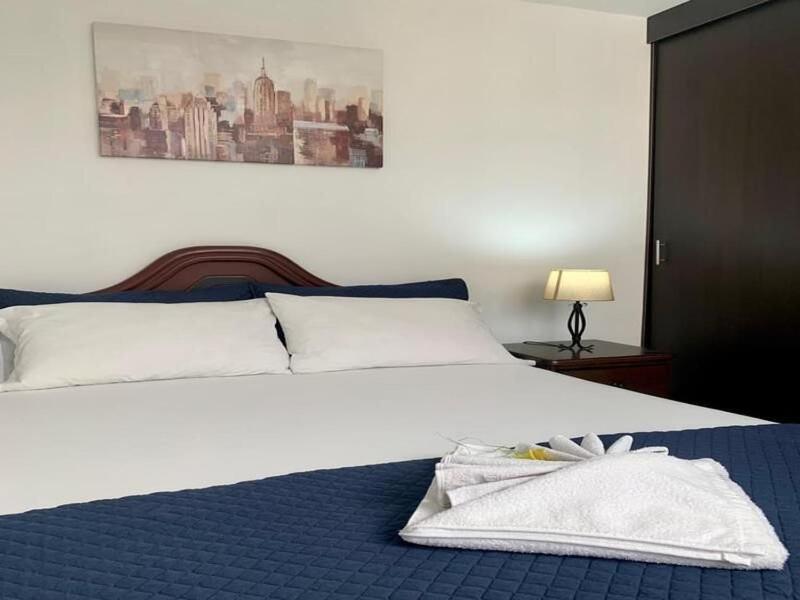 1 dormitorio con 1 cama blanca grande con manta azul en Hab Nawi con Aire Acondicionado, en Cali