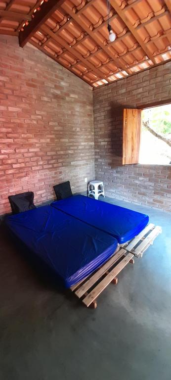a large blue bed in a room with a brick wall at Cantinho HAKUNA MATATA-Vale do Capão a 5 min da Vila in Vale do Capao