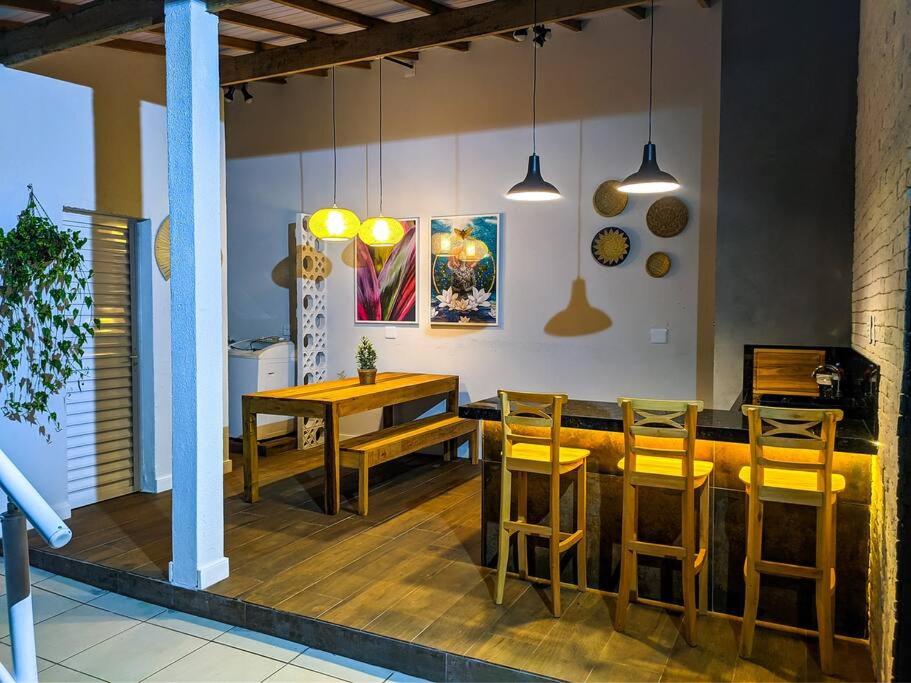 - une salle à manger avec une table et des chaises en bois dans l'établissement CASA JD SÃO LOURENÇO PISCINA AR WI-FI TV PRAIA, à Bertioga