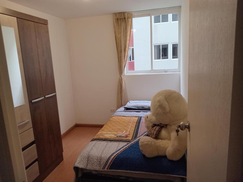 um urso de peluche sentado numa cama num quarto em Departamento amoblado 9vno piso em Lima