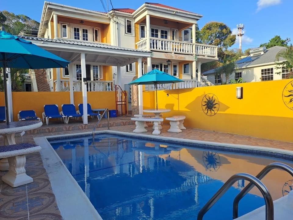 a house with a swimming pool and a yellow wall at Villa Riana Barbados in Christ Church