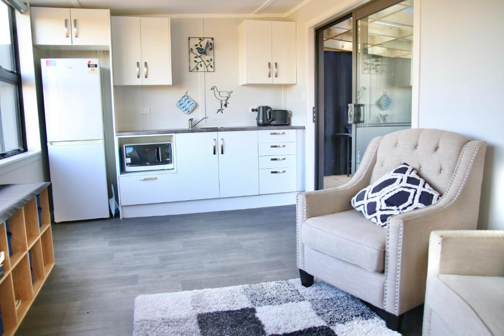 a living room with a chair and a refrigerator at The Bird House Tiny Home in Ngaruawahia