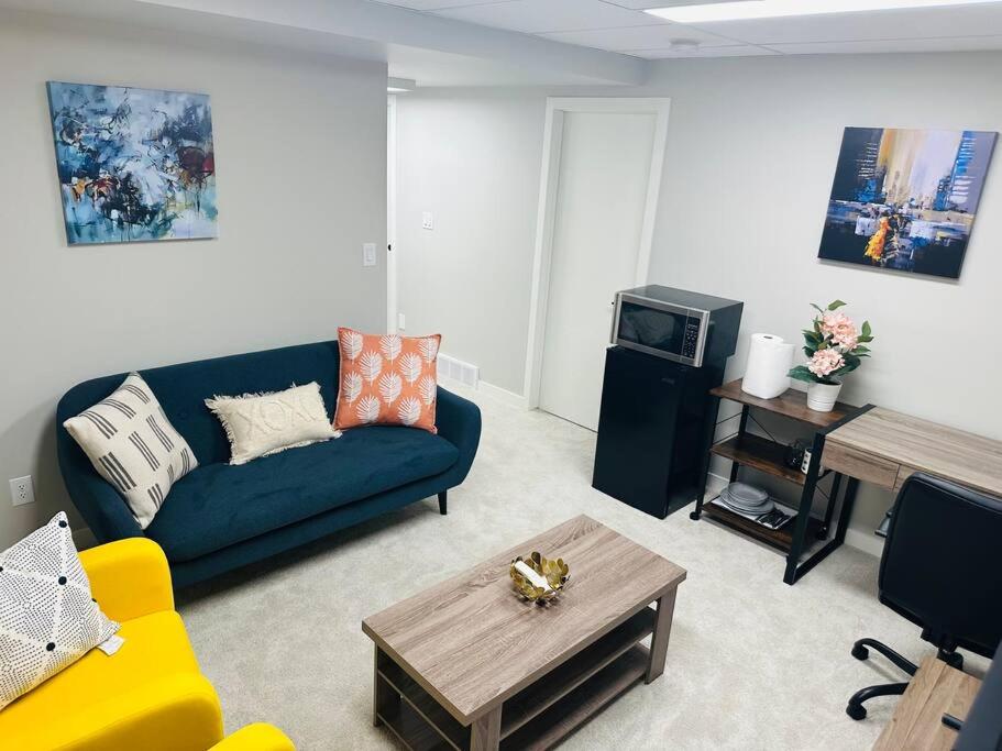 ein Wohnzimmer mit einem blauen Sofa und einem TV in der Unterkunft 1 Bedroom modern basement suite with private entrance in Winnipeg
