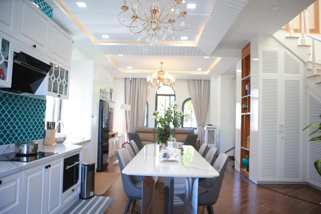 uma cozinha e sala de jantar com uma mesa branca e cadeiras em Le Gia Villa 1, sang trọng, bên hồ, hướng biển, 3PN, 3 phòng tắm, Novaworld Phan Thiết cho kỳ nghỉ gia đình em Phan Thiet